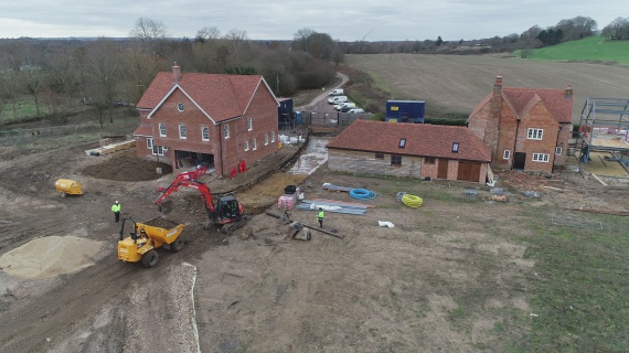 Arial view showing a road being dug out between two houses.